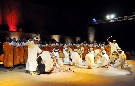 Troupe d'Ahwach en formation, joueurs de tambours agenouillés et danseurs debout, scène nocturne, Ouarzazate 2012.