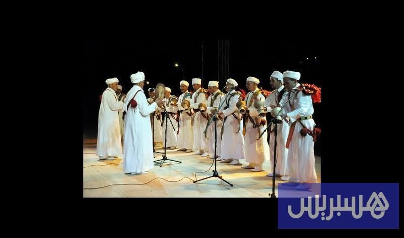 Hommes en djellabas blanches avec tambours sur cadre (bendir), scène nocturne du Festival national des arts d'Ahwach, Ouarzazate, 19–21 octobre 2012. Photo de une du reportage Hespress.