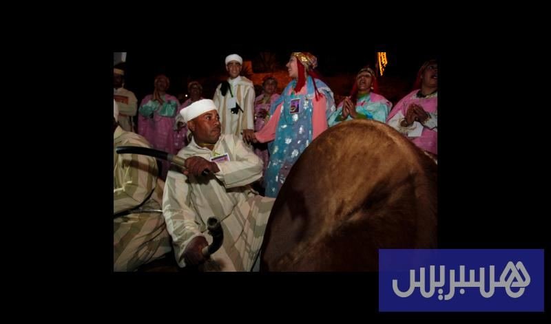 Troupe d'Ahwach (hommes en blanc aux tambours, femmes en robes colorées) au pied des remparts de la Kasbah Taourirt lors de l'ouverture du festival, 15 novembre 2013.