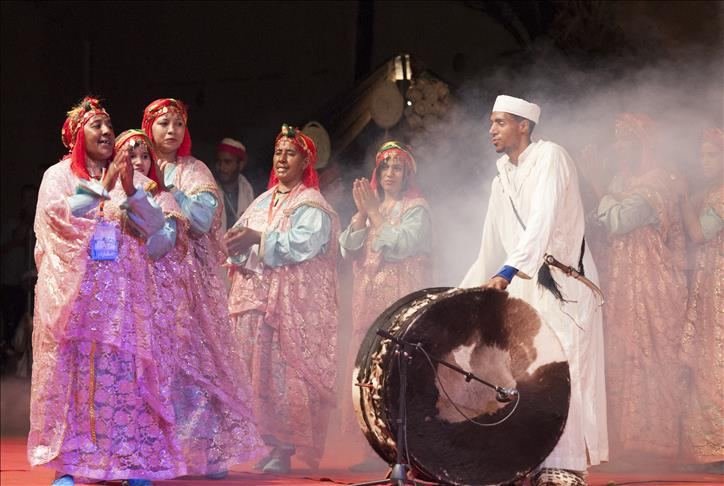 Joueur de grand tambour (ganga) en djellaba blanche entouré de danseuses en robes roses et de musiciens, fumée de scène, clôture du festival 2015.