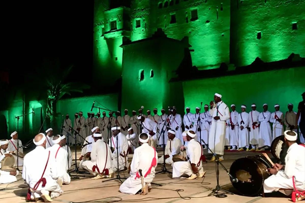 Troupe d'Ahwach en blanc en demi-cercle sur tapis rouges devant la Kasbah Taourirt éclairée en vert, soirée d'ouverture, 10 juin 2022.